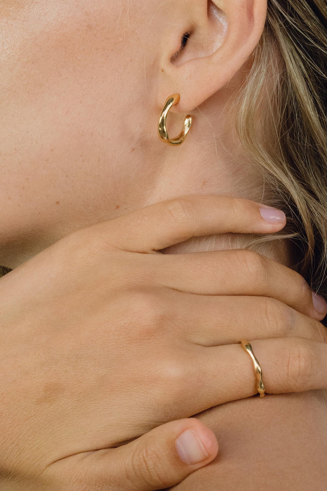 LUMI small earrings crafted from recycled gold, ethical handmade jewelry with a shiny surface, worn by a model.