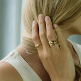 Close-up of a hand with two ethical handmade rings, showcasing sustainable 18k gold-plated recycled silver jewelry.
