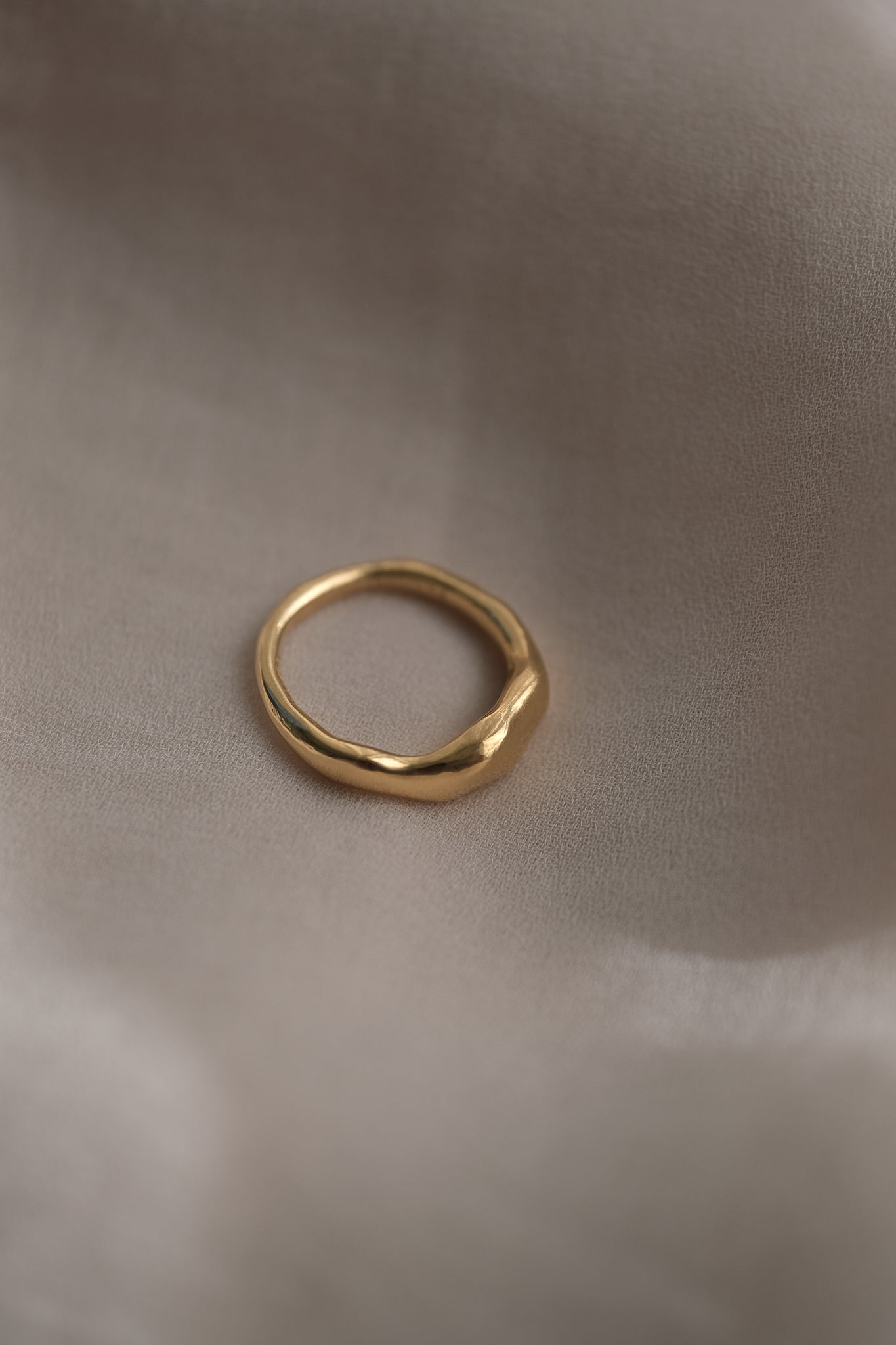 MIRU ring made from recycled gold, showcasing a natural shiny surface on a soft fabric background.