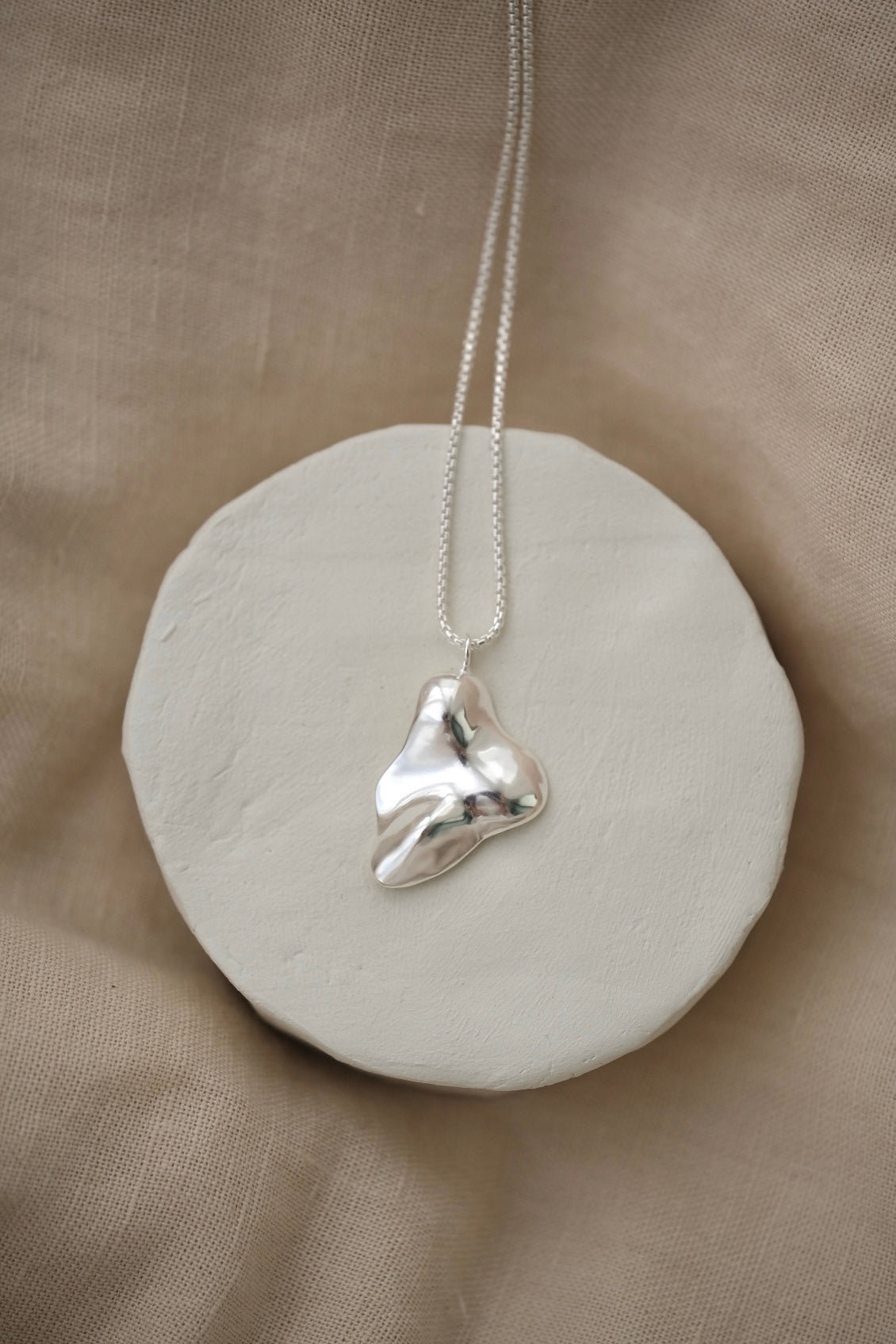 Handmade MOA necklace featuring a unique recycled silver pendant on a minimalist display.