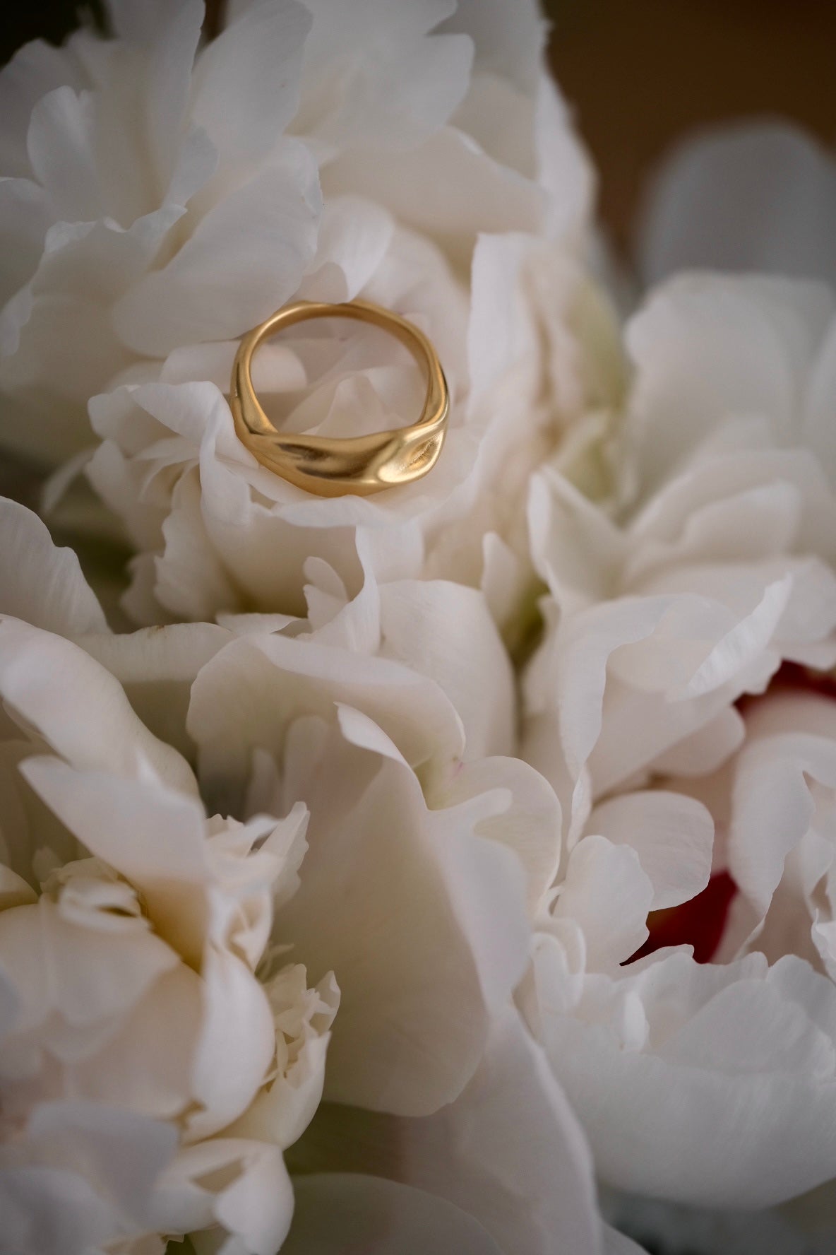 YERERA big ring in 18k gold-plated brass, nestled among white peonies, showcasing ethical and sustainable jewelry craftsmanship.