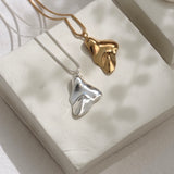 Handmade MOA necklace featuring 18k gold-plated and recycled silver pendants on a display showcasing ethical jewelry.