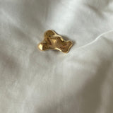 Handmade MOA brooch in 18k gold-plated recycled silver, featuring a natural shiny surface, on a soft fabric background.